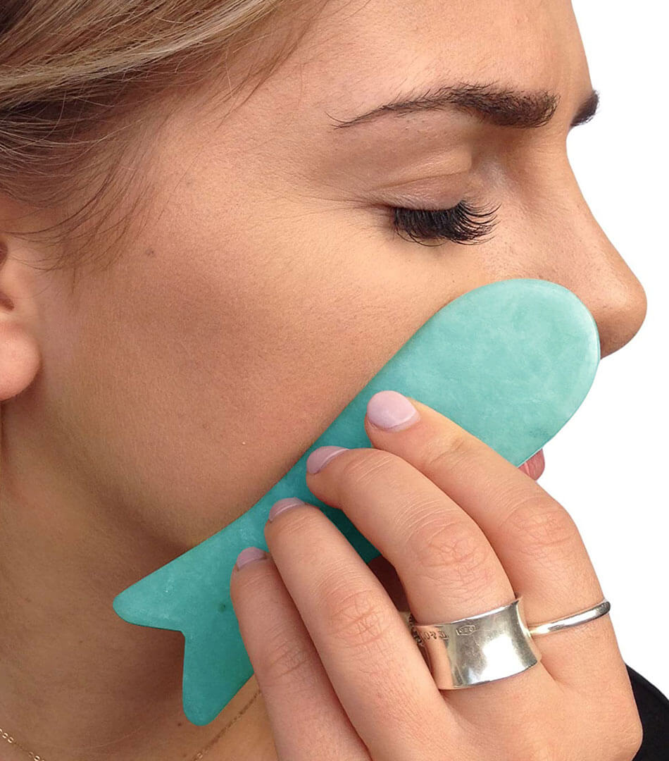 women applying guasha on her face