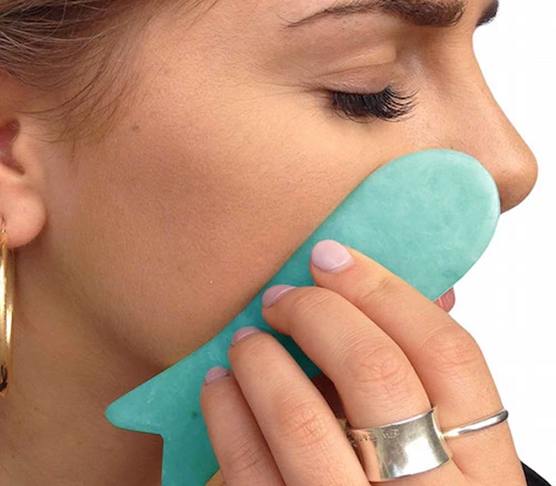 woman using fish-shape gua sha lifting tool