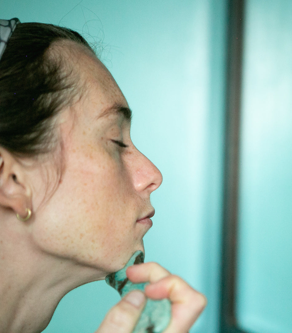 woman using fish shape gua sha lifting tool